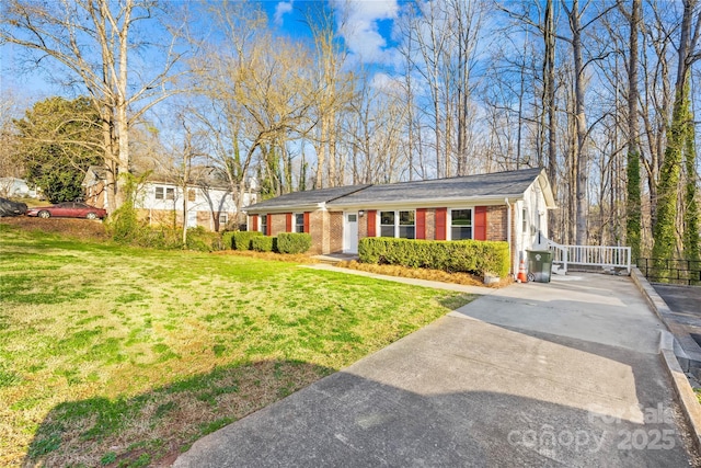 view of front of house with brick siding, concrete driveway, a front lawn, and fence