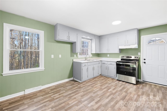 kitchen with visible vents, a sink, under cabinet range hood, stainless steel electric stove, and light countertops