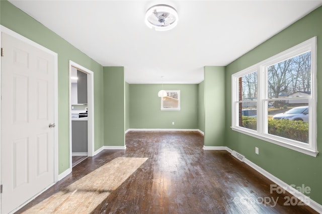 unfurnished room with visible vents, baseboards, and wood-type flooring