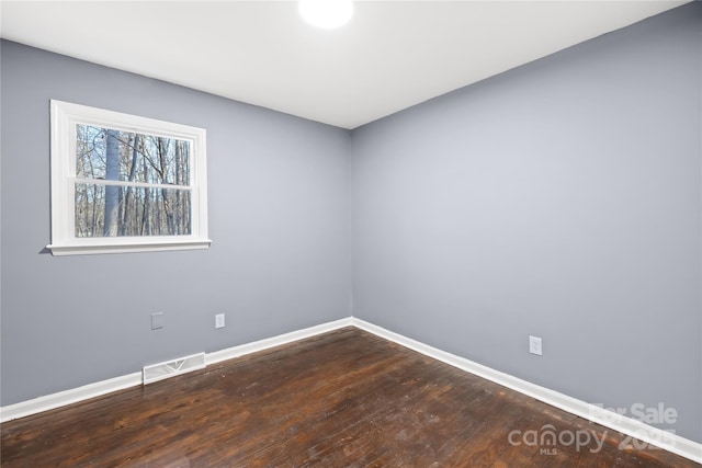 unfurnished room featuring visible vents, baseboards, and wood finished floors