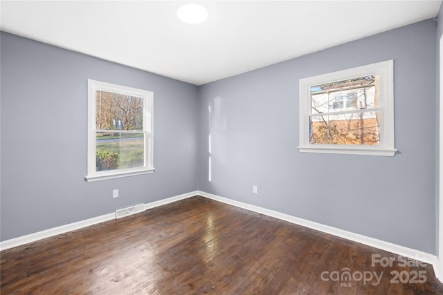 unfurnished room featuring visible vents, plenty of natural light, baseboards, and dark wood-style flooring