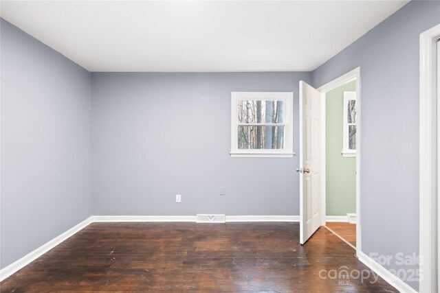 unfurnished room with visible vents, baseboards, and wood finished floors