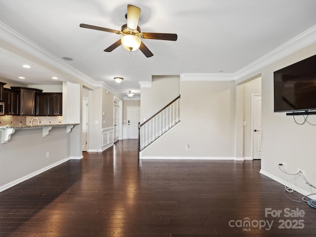 unfurnished living room with stairway, dark wood-type flooring, ceiling fan, and ornamental molding