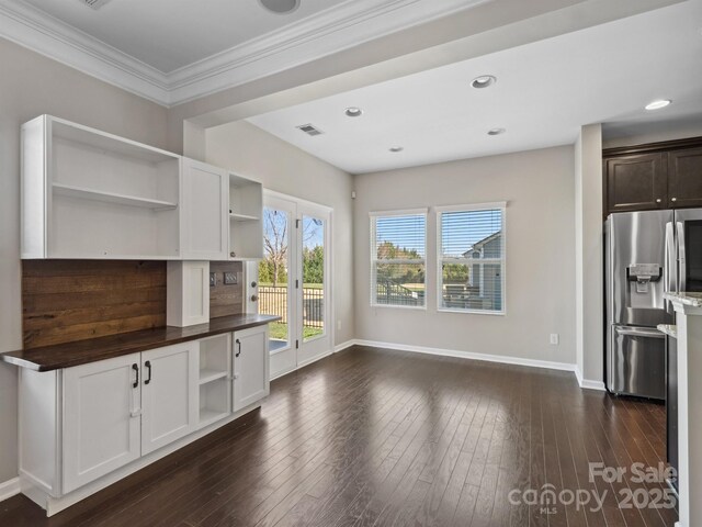 kitchen with visible vents, dark wood-type flooring, open shelves, stainless steel fridge, and baseboards