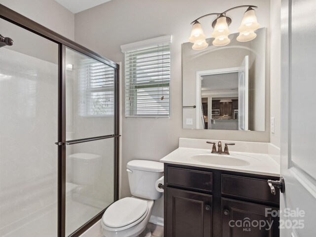 full bath featuring vanity, a shower stall, toilet, and an inviting chandelier