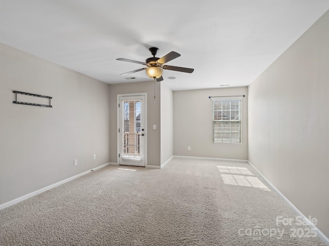 spare room featuring a ceiling fan, light colored carpet, a wealth of natural light, and baseboards