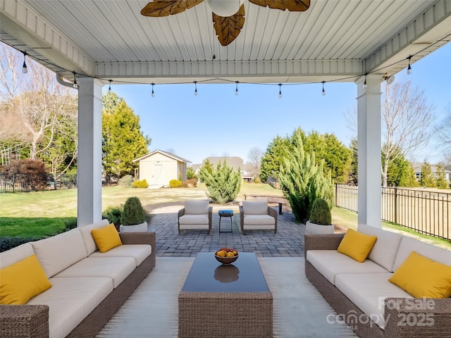 view of patio / terrace with an outbuilding, an outdoor living space, fence, a shed, and ceiling fan