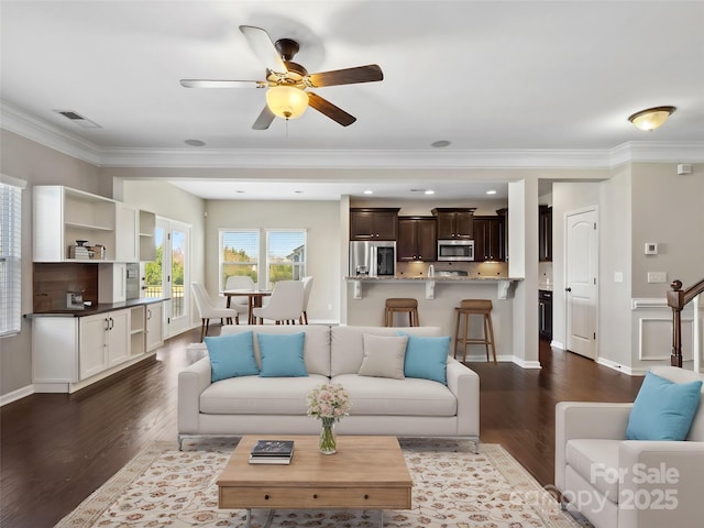 living room featuring visible vents, dark wood-type flooring, ceiling fan, and ornamental molding