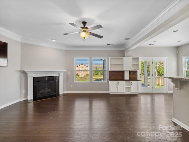 unfurnished living room with dark wood finished floors, baseboards, crown molding, and a ceiling fan