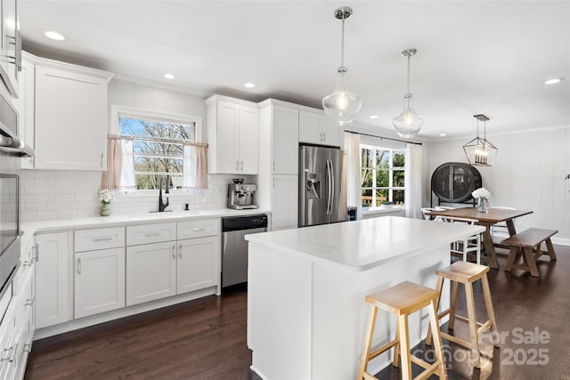 kitchen featuring dark wood-style floors, a sink, white cabinets, appliances with stainless steel finishes, and tasteful backsplash