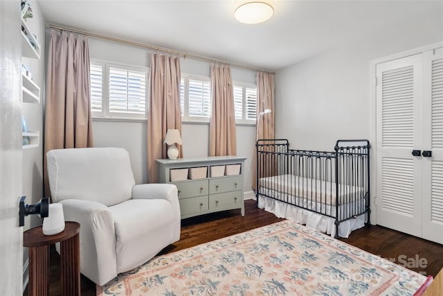 bedroom featuring a closet, a crib, and wood finished floors