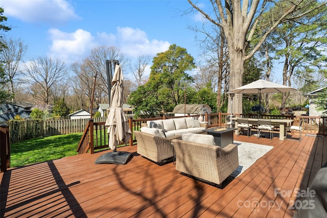 wooden deck with outdoor dining space, an outdoor living space with a fire pit, and a fenced backyard