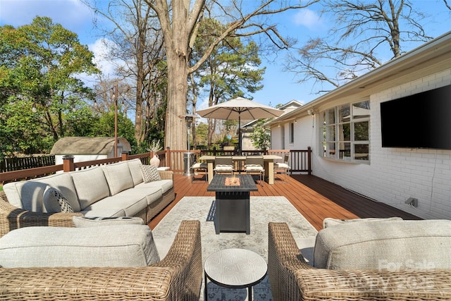 wooden deck with a storage unit, an outdoor living space with a fire pit, and an outdoor structure