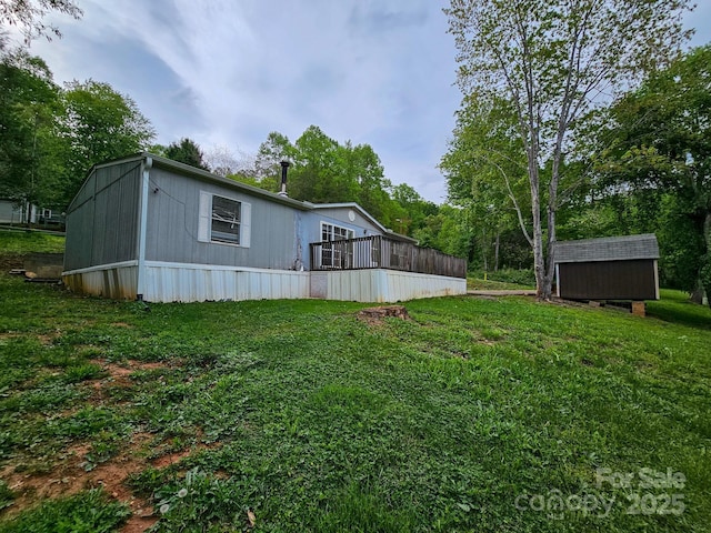 rear view of property with an outbuilding, a lawn, a deck, and a storage shed