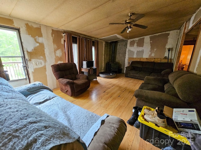 living area featuring a wood stove, hardwood / wood-style flooring, and ceiling fan