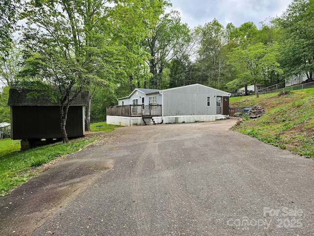 exterior space with a deck, an outdoor structure, a shed, and aphalt driveway