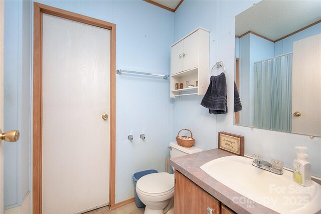 bathroom with vanity, toilet, a shower with curtain, and ornamental molding