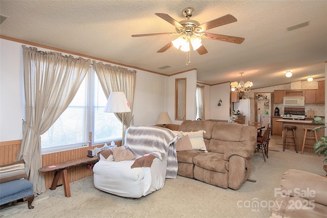 living area with a wainscoted wall, light carpet, a textured ceiling, and vaulted ceiling