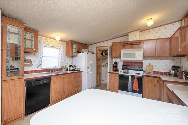 kitchen featuring wallpapered walls, lofted ceiling, white appliances, a textured ceiling, and a sink