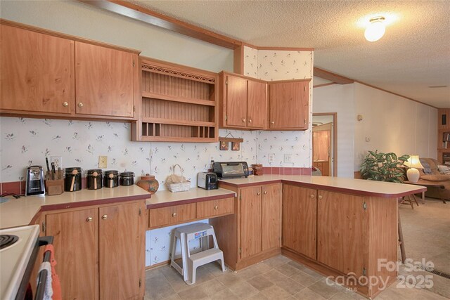 kitchen featuring open floor plan, a peninsula, wallpapered walls, and range