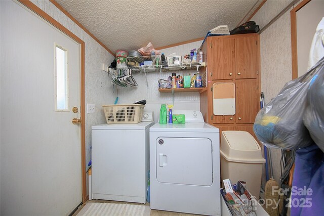 clothes washing area with washer and clothes dryer, laundry area, a textured ceiling, and crown molding