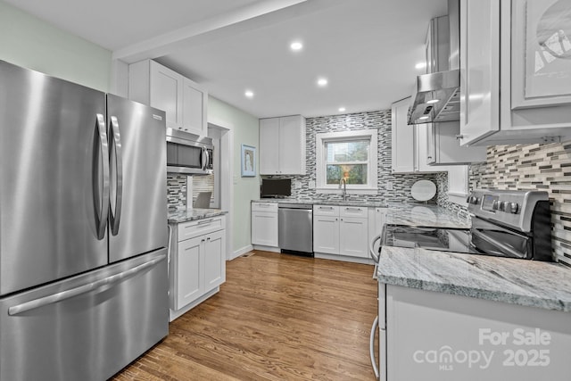 kitchen featuring decorative backsplash, light wood-style floors, appliances with stainless steel finishes, and white cabinets