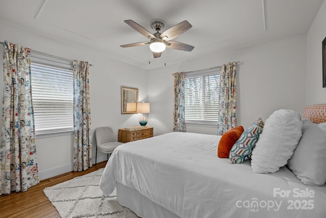 bedroom with ceiling fan, visible vents, baseboards, and wood finished floors