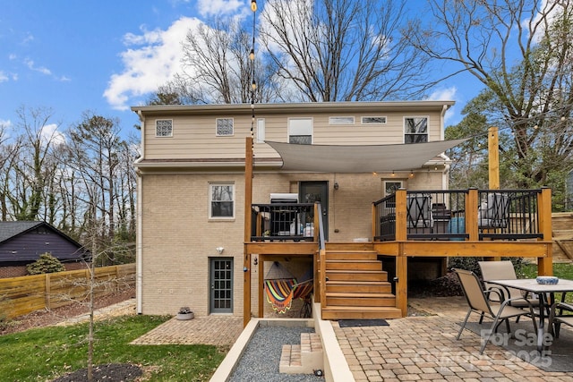 rear view of house with a patio area, a wooden deck, brick siding, and fence