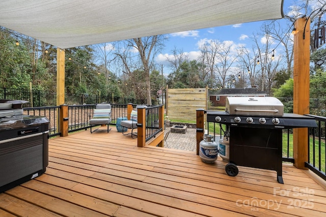 wooden deck with area for grilling and a fenced backyard