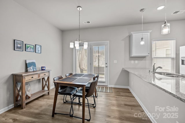 dining space featuring visible vents, baseboards, and wood finished floors