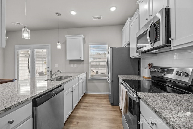 kitchen with visible vents, backsplash, white cabinets, stainless steel appliances, and a sink