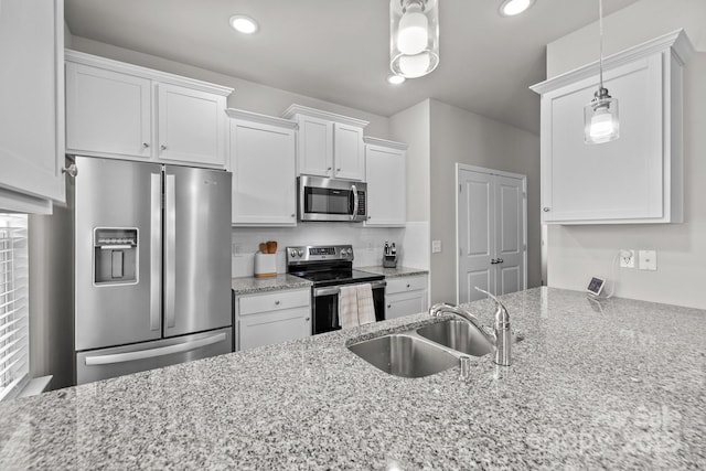 kitchen with light stone counters, white cabinets, appliances with stainless steel finishes, and a sink