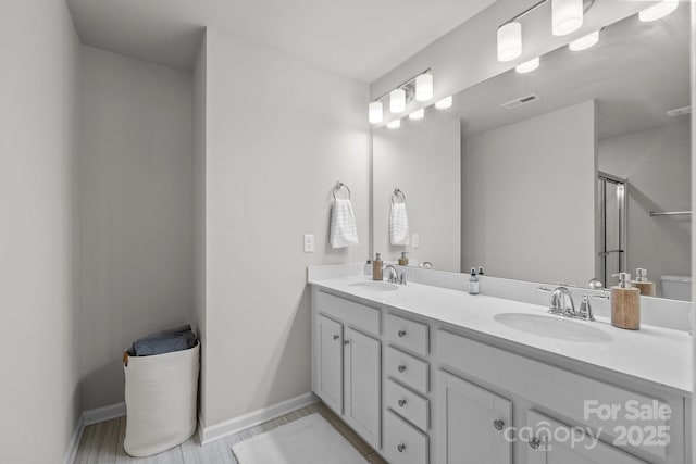 bathroom featuring double vanity, baseboards, visible vents, and a sink