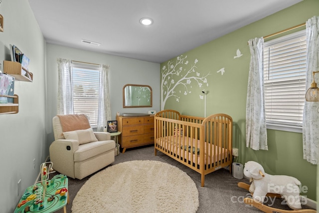 carpeted bedroom with a crib, recessed lighting, and visible vents