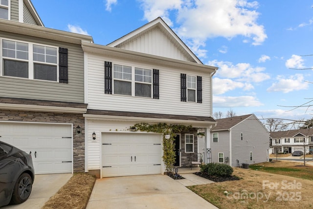 multi unit property featuring a garage, stone siding, board and batten siding, and concrete driveway