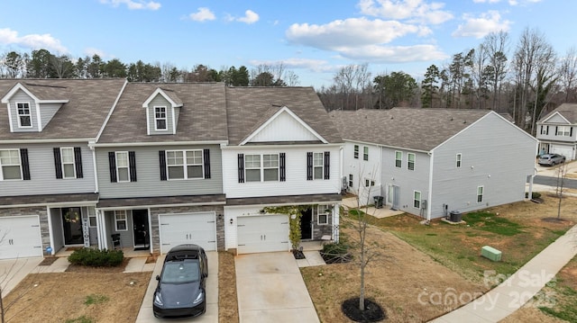 multi unit property featuring concrete driveway, an attached garage, central AC unit, and a shingled roof