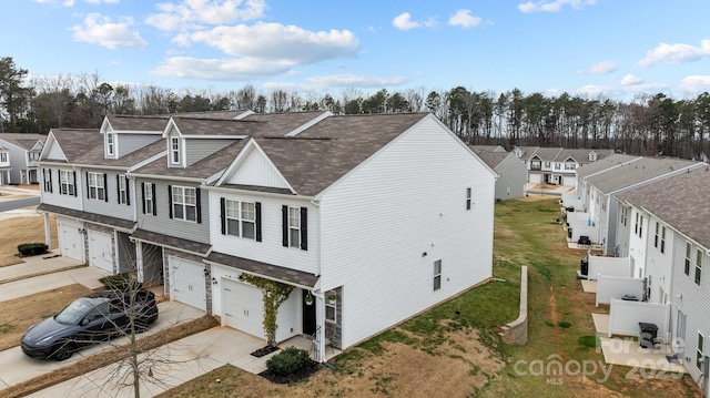 view of front facade with a residential view, concrete driveway, a garage, and roof with shingles