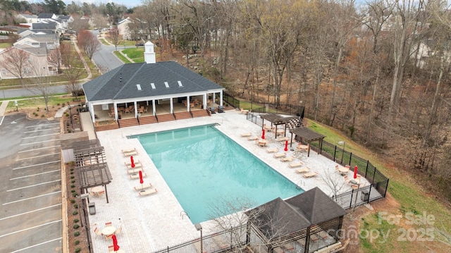 community pool with an outbuilding, an exterior structure, a patio, and fence