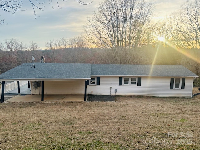 rear view of house with a patio area, a yard, and roof with shingles