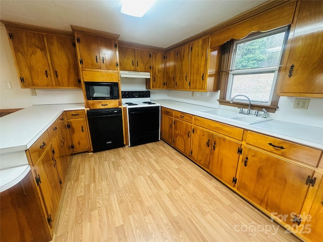 kitchen with light wood-type flooring, black appliances, a sink, under cabinet range hood, and brown cabinetry