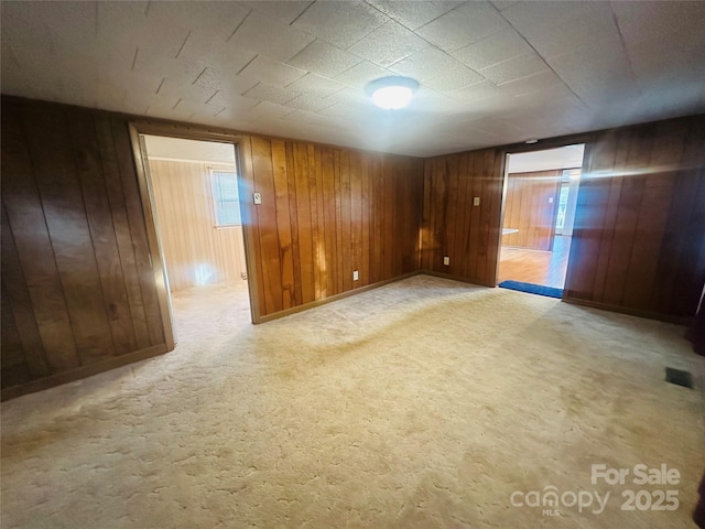 unfurnished room featuring wooden walls, carpet flooring, and baseboards