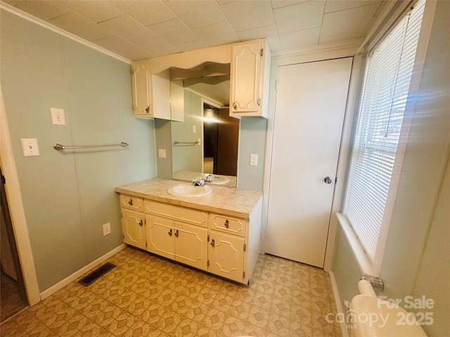 bathroom featuring tile patterned floors, visible vents, ornamental molding, baseboards, and vanity