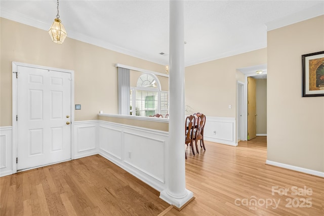 entrance foyer featuring wainscoting, light wood finished floors, and ornamental molding