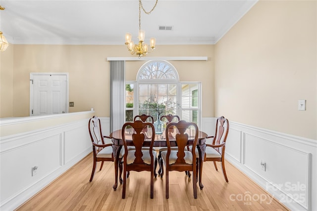 dining area featuring wainscoting, light wood-style floors, and an inviting chandelier