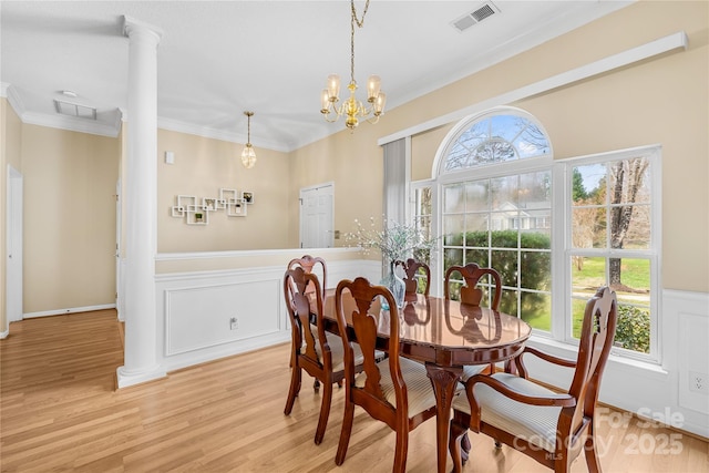 dining room featuring visible vents, light wood-type flooring, ornamental molding, wainscoting, and an inviting chandelier