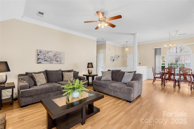 living room with a wainscoted wall, ceiling fan with notable chandelier, crown molding, and light wood-style floors