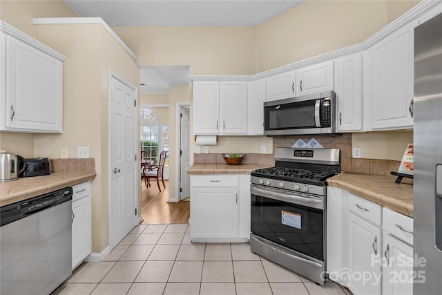 kitchen with white cabinets, appliances with stainless steel finishes, and tile counters