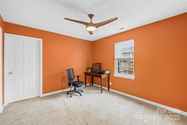 office space with visible vents, carpet floors, baseboards, and a ceiling fan