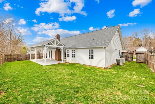 back of property featuring a yard, a fenced backyard, a chimney, a gazebo, and a patio area