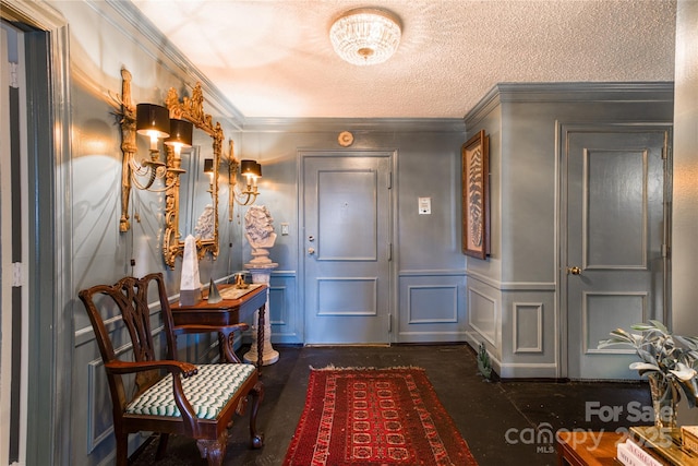 foyer entrance featuring a wainscoted wall, a textured ceiling, crown molding, and a decorative wall